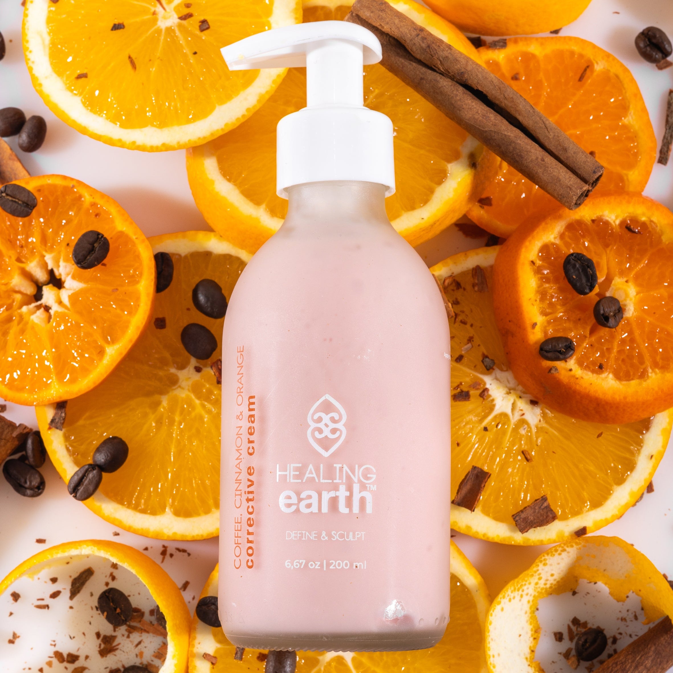 Bottle of Healing Earth Corrective Cream with oranges and cinnamon sticks on a white background